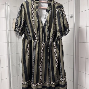 Klänning med kedjamönster XXL - Klänning med kedjamönster XXL  Polyester.   Använt ett par gånger, bra skick.  Oliv, svart & beige.   Storlek XXL. 