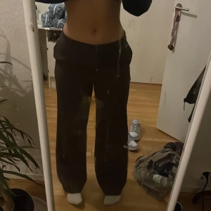 Lågmidjade kostymbyxor  - INSYDDA I MIDJAN OCH UPPSYDDA, skriv om mått.  Ett par lågmidjade bruna kostymbyxor