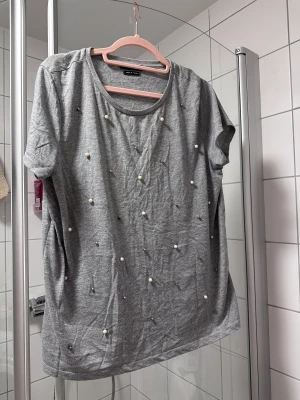 T-skjorta med pärlor - Grå t-skjorta med pärlör och silver ballong.   Fint skick.  Storlek XL