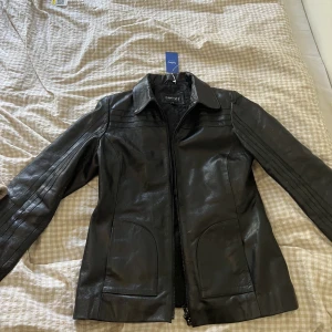 Skinnjacka  - Så snygg skinnjacka i äkta läder ifrån hollies. Aldrig använd med lapp kvar (köpt på sellpy) ❤️storlek 40 i herrmodell men motsvarar en S/m