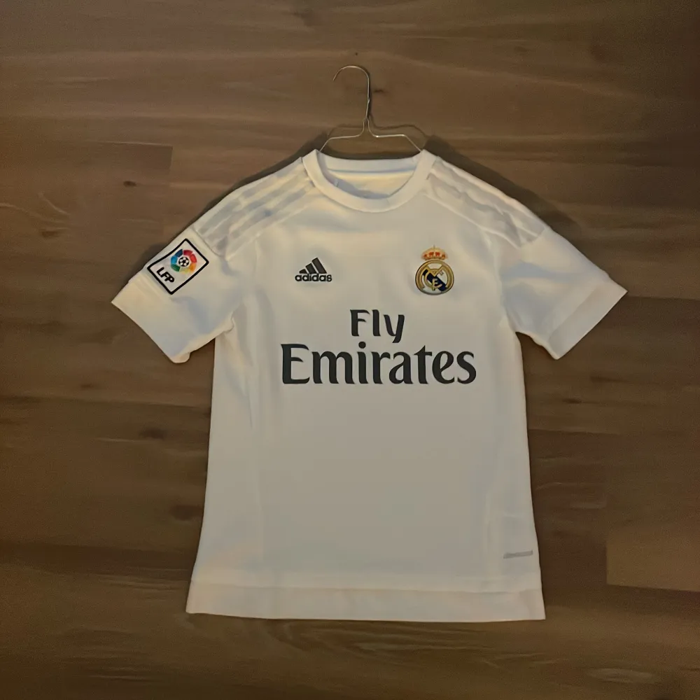 Säljer denna Real Madrid tishan för att den är för liten. Storleken är lite oklar men skulle säga att det är xs. På andra bilden står det lite olika storlekar. Skriv om du har några frågor. . T-shirts.