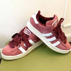 Adidas Campus 00’s Rosa/Röd - Hej, säljer dessa väldigt populära Adidas Campus sneakers. Skorna är använda en gång och är i perfekt skick. Unik färg och väldigt snygg design. Slutsåld i alla storlekar. Storlek 38 och True To Size. Pris inte hugget i sten. Hör av dig vid intresse!