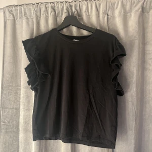 Tröja - Söt svart T-shirt med volang vid ärmarna, använt typ en gång och fortfarande nytt skick💕 Skriv för mer bilder!
