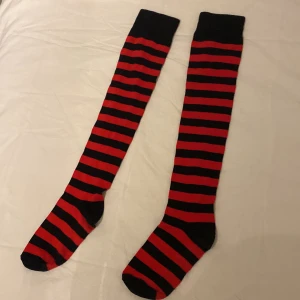 Thigh highs - Röda-svarta randiga thigh highs som har använts endast en gång därav mycket bra skick. Köpt i Blufox med orgiginalpriset 79kr. Kontakta vid frågor! 