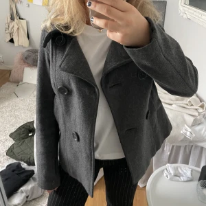Jacka - Kort mörkgrå kort vår/höstkappa från H&M. Jackan har jättefina detaljer med knappar på fram och baksidan!!😊