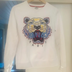 Kenzotröja i Nyskick - Jag säljer min fina Kenzotröja då jag bara har fått användning för den två gånger i hopp om att någon annan ska få glädje av den. Den är vit i storlek M men passar mig som är XS.   Nypris: 2200 Mitt pris: 900  Köparen står för frakt 