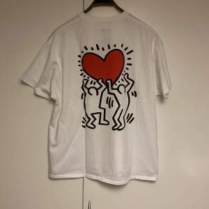 Keith Haring tisha i dunder skick köpt på Urban Outfitters. Hans ikoniska konst på ryggen samt en liten logga där fram av samma motiv. 