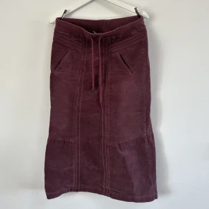 Lila mancesterkjol  - Medellång kjol i lila/burgundy Manchester. Dragsko i midjan.