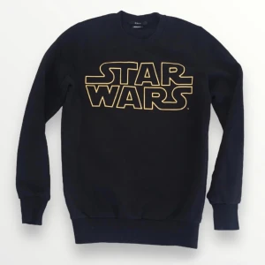 Star Wars x FBSN Slim Fit tröja i strl Xs - Svart tröja med Star Wars-tryck i gult. Storlek Xs, Slim Fit. Normal i storleken. Bra skick, finns lite slitage efter tvätt, ffa på krage/muddar samt trycket som har nån liten spricka i färgen.