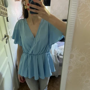 Volang blus  - Jättefin ljusblå volangblus! Den är stretchigt material så skulle säga att den passar en s/m💙💙