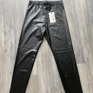 Leggings  - Leggings i konstläder från NA-KD, prislappen kvar aldrig använda i storlek s men skulle också passa xs.