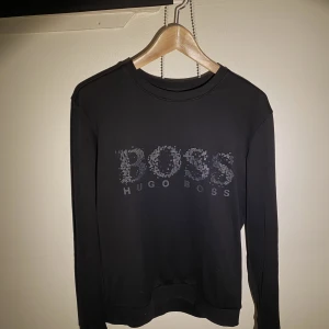 Hugo Boss Sweatshirt  - Hej, säljer en väldigt snygg Hugo Boss tröja. Den är i använt skick men fortfarande fin. Den har snyggt mönster på bröstet. Storlek M men passar även S. Nypris runt 2000kr i deras butik i Täby Centrum. Priset är inte hugget i sten. Hör av dig vid f