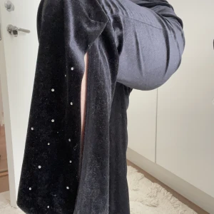 Y2k rhinestones byxor - Svarta i sammetstyg. Mjuka. Rhinestones i slutet av byxorna med slits. Aldrig använt. Köpt secondhand. Inga defekter. Står ingen storlek i byxorna men uppskattas S. Jag är 163 cm lång 🖤