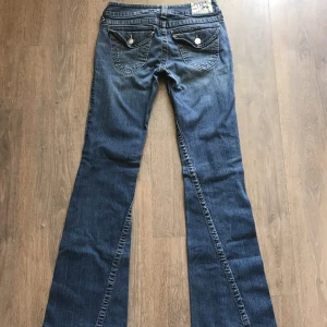 True Religion Jeans Bootcut - Ett par eftertraktade True Religion Jeans i flared/bootcut modell med snygga fickor där bak och lowwaist, detta par är i strl 29. Inga defekter, 9/10 skick. Skriv om ni har frågor!