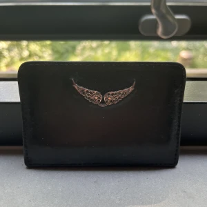 ZADIG KORTHÅLLARE - En svart korthållare från zadig&voltaire. Välanvänd men fortfarande snygg och fungerar som den ska. Vingarna har tappat lite färg men inget som förstör💕