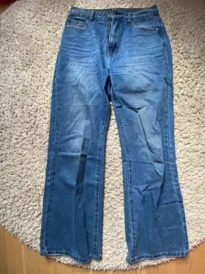 Highwaist, medelblå jeans som är lite utsvängda.