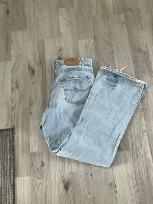 Ljusblå raka Jack & Jones - Säljer ett par ljusblå Jackie Jones med raka ben och råa, fransiga benslut. Klassisk femficksmodell  Jeansen är i 100% bomull och har en avslappnad vintagekänsla.