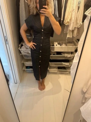  Snygg jeans klänning med knappar - Intressekoll på denna snygga jeansklänning med v-ringning och korta ärmar. Klänningen har en figurnära passform, knappar längs hela framsidan och en slits nedtill. Perfekt för dig som gillar en stilren och trendig look. Ny med prislapp i storlek Xs passa mig som bruka ha S. Skriv innan du köper.