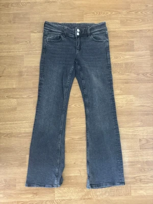 Grå bootcut lågmidjade jeans med dubbla knappar - Gina tricot lågmidjade gråa bootcut jeans. Använt 2 gånger så är i mycket bra skick. Skickas ut inom 1-2 dagar