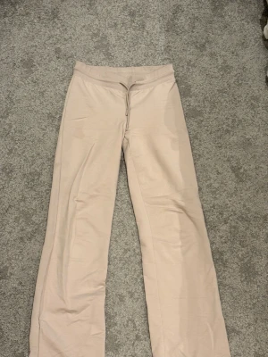 Beige mjukisbyxor  - Säljer ett par beige mjukisbyxo. Byxorna har en avslappnad passform och är tillverkade i ett mjukt, stretchigt material som är perfekt för chill dagar. Perfekta för dig som gillar en enkel och clean stil.