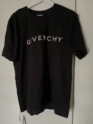 Svart Givenchy t-shirt - Snygg svart t-shirt från Givenchy med vit logga tryckt över bröstet. Klassisk rund halsringning och korta ärmar. Tillverkad i mjuk bomull för en skön och avslappnad look.