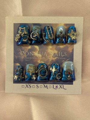 BlueAbyss(XL);Short Duck Nails - Unika handgjorda press-on naglar i metallicblå färg. Naglarna har coola 3D-dekorationer i silver som stjärnor, kedjor, säkerhetsnål och kors. Trendiga och designen är edgy med mycket detaljer. Perfekt för dig som vill sticka ut med din nagelstil.XL: 17 mm, 13 mm, 14 mm, 12 mm, 11 mm 