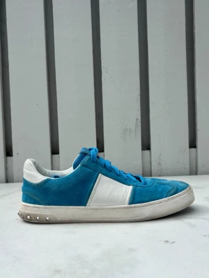 valentino flycrew - Snygga blåa sneakers från valentino med vit sula och vit sidopanel. Ovandelen är i mocka och textil, med klassisk snörning och låg profil. Sulan har ett unikt mönster undertill. Perfekta för dig som gillar retrostil och färg. Hör av om du har några frågor. Pris kan diskuteras 