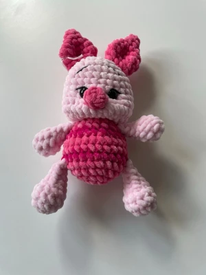 Rosa mjukisdjur gris - Söt rosa mjukisdjur i form av en gris med stora öron och svart broderade ögon. Kroppen är virkad i mjukt plyschmaterial med ljusrosa ben och huvud samt mörkare rosa mage, nos och öron. Perfekt som gosedjur eller dekoration. Nasse inspirerad 23 cm