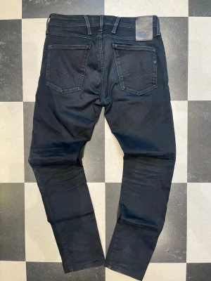  slim fit jeans från Replay - Snygga slim fit jeans från Replay med klassisk femficksdesign och diskreta slitningar. Jeansen har raka ben och är tillverkade i ett stretchigt bomullsmaterial för extra komfort. Perfekta för en trendig och avslappnad look. W31 L30