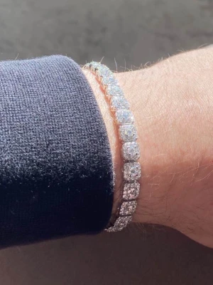 Glittrigt tennisarmband i silver - Diamantarmband äkta silver. Snyggt tennisarmband med briljantslipade stenar. Armbandet har en klassisk och stilren design som verkligen blänker i ljuset. Perfekt för dig som gillar att sticka ut med lite extra bling på handleden. Längd: ca 18 cm Bredd:5mm. Priset är inte hugget i sten så kom gärna med förslag.
