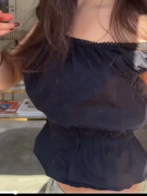 Svart offshoulder topp - Snygg svart offshoulder topp med volangkant nedtill och elastisk midja. Toppen har korta puffärmar och en söt spetsdetalj längs urringningen. 