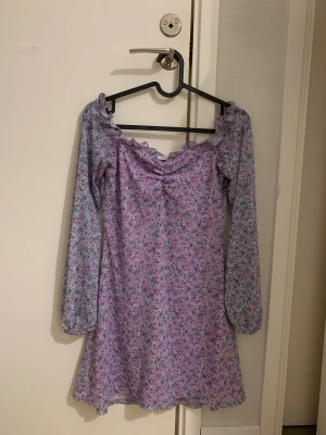 Ljuslila blommig klänning från Nelly - En supersöt ljuslila kort klänning från Nelly i storlek XS. Klänningen har ett blommigt mönster i lila och blå toner, långärmade ärmar och volangdetaljer vid halsringningen. Har endast använt 2 gånger, är i mycket bra skick. Materialet är mjukt och lätt polyester, perfekt för sommar dagar!💜