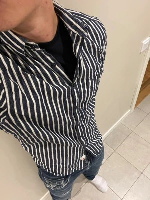 Randig skjorta från Replay - Säljer en snygg blå och vit randig skjorta från Replay. Skjortan har klassisk krage, bröstficka och knappar framtill. Tillverkad i ett lätt och skönt material, perfekt för dig som vill ha en stilren men avslappnad look.💋Modellen bär storlek M och är 181 cm lång och väger 76 kg kom gärna vid frågor eller funderingar💋