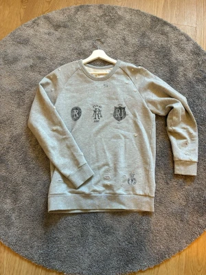 Grå sweatshirt från Replay - Grå sweatshirt från Replay. Tröjan har rund halsringning, ribbade muddar och avslappnad passform. Tillverkad i mjukt bomullsmaterial, perfekt för en casual stil.