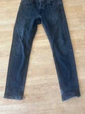 Svarta slim fit jeans - Snygga svarta slim fit jeans med klassisk femficksdesign och dragkedjegylf. Jeansen har en något tvättad look och raka ben. Perfekta för en stilren och avslappnad outfit.