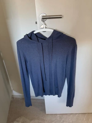 Mörkblå kasmir hoodie med huva - En stilren mörkblå hoodie i tunt, mjukt material. Hoodien har långa ärmar, dragsko i huvan och en enkel, minimalistisk design utan tryck eller logga. Perfekt för dig som gillar en clean look och vill ha något lätt att slänga på sig.