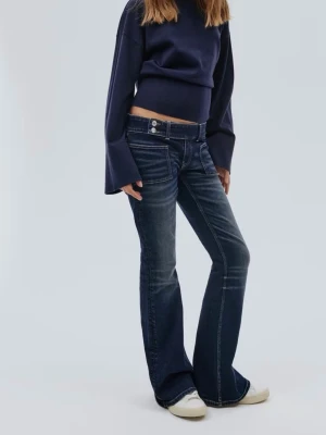 Mörkblå bootcut jeans - Snygga mörkblå bootcut jeans med markerade slitningar och kontrastsömmar. Jeansen har låg midja, dubbla knappar och klassiska fem fickor. Perfekta för en trendig och avslappnad look.