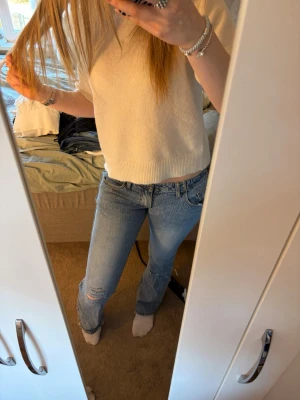 Ljusblå lågmidjade bootcut jeans med slitning - Säljer ett par ljusblå jeans med bootcut passform och slitning vid knät. Jeansen har klassisk femficksdesign och normal midja. Perfekta för en avslappnad och trendig look. Materialet är denim i bomull. liten reva vid rumpan som inte syns så mycket (sista bilden) Storlek S, jag är 175 cm