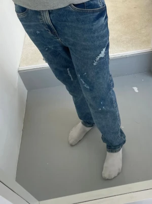 Blåa slitna jeans med rak passform - Säljer ett par blåa jeans med rak passform och slitna detaljer på benen. Passar bra med en grå hoodie eller något annat. VET INTE DIREKT STORLEK MEN JAG ÄR 165 LÅNG OCH SITTER LITE FÖR STORT FÖR MIN STIL MEN FUNKAR SÄKERT FÖR NÅGON SOM ÄR KORTARE ELLER LÄNGRE BEROENDE PÅ HUR MAN VILL ATT DE SKA SITTA 