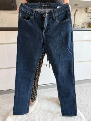 Mörkblå jeans från MAPP strl 28 - Snygga mörkblå jeans från MAPP med klassisk femficksdesign och raka ben. Jeansen har guldfärgade sömmar och stängs med knapp och dragkedja. Perfekta till en avslappnad och trendig look.