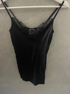 Linne med spets  - Svart linne med tunna axelband och vacker spetsdetalj vid urringningen. 
