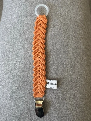 Virkad napphållare  - Virkad, terrakotta färgad napphållare, virkad av mig i 100% bomullsgarn med metallclips och silikonring.  Mönsterskapare: animo.design