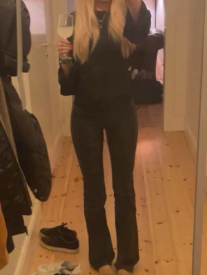 Svart topp med öppen rygg och knyt - Säljer en svart topp med öppen rygg och knyt i ryggen. Toppen har långa ärmar och en croppad passform som ger en trendig look. Perfekt för dig som vill sticka ut lite extra.