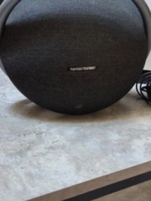 Harman Kardon rund bärbar högtalare - Snygg och kraftfull bärbar högtalare från Harman Kardon i rund form. Högtalaren är klädd i mörkgrått tyg och har ett robust handtag för enkel transport. Perfekt för att ta med sig musiken överallt och levererar riktigt bra ljud. Med laddare 