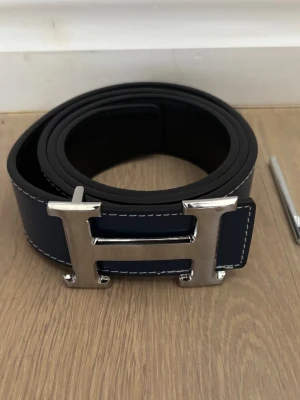 H bälte - Säljer nu ett riktigt snyggt bälte med den ikoniska H loggan på framsidan! | Väldigt bra skick, nyskick? | Passar bra till fest-vardag. | Mörkblå färg, möjligt att använda det utan och in där det blir svart. | Storlek 115. | Släng iväg en signal vid funderingar så svarar jag snabbt. |