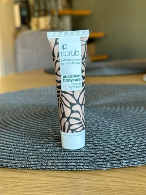 Lip scrub från Australian Bodycare - Exfolierande lip scrub från Australian Bodycare i en smidig tub. Tuben har ett stilrent mönster i beige och svart och är perfekt för att få mjuka och släta läppar. Inspirerad av naturen och enkel att använda.