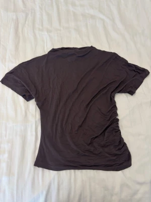 Brun t-shirt från lager 157 - En enkel brun t-shirt från lager 157 i mjuk bomull. Modellen har korta ärmar och klassisk rund hals. Perfekt basplagg att matcha med jeans eller kjol. T-shirten har en normal passform och är riktigt skön att bära.