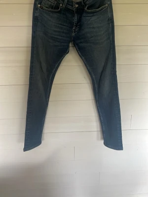 Mörkblå skinny jeans med hög midja - Säljer ett par mörkblå skinny jeans med hög midja och klassiska fem fickor. Jeansen har en snygg tvätt med lätt slitning och smal passform hela vägen ner. Perfekta till en avslappnad eller trendig look.