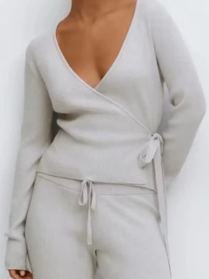 Grått ribbat loungewear - Mysigt loungeweari ljusgrått med omlottopp och knytband i midjan samt matchande byxor med dragsko. Setet är ribbstickat och har långa ärmar och ben, perfekt för avslappnade dagar hemma.