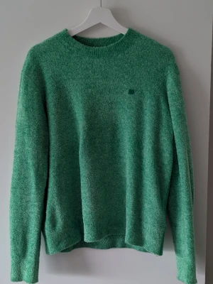 Tröja Acne Studios - Mysig grön stickad tröja från Acne Studios med rund halsringning och deras ikoniska lilla ansiktslogga på bröstet. Tröjan har en fluffig, mjuk textur. Använd endast enstaka gång så är i ett mycket gott skick. Stl M och "boxig" i modellen. 